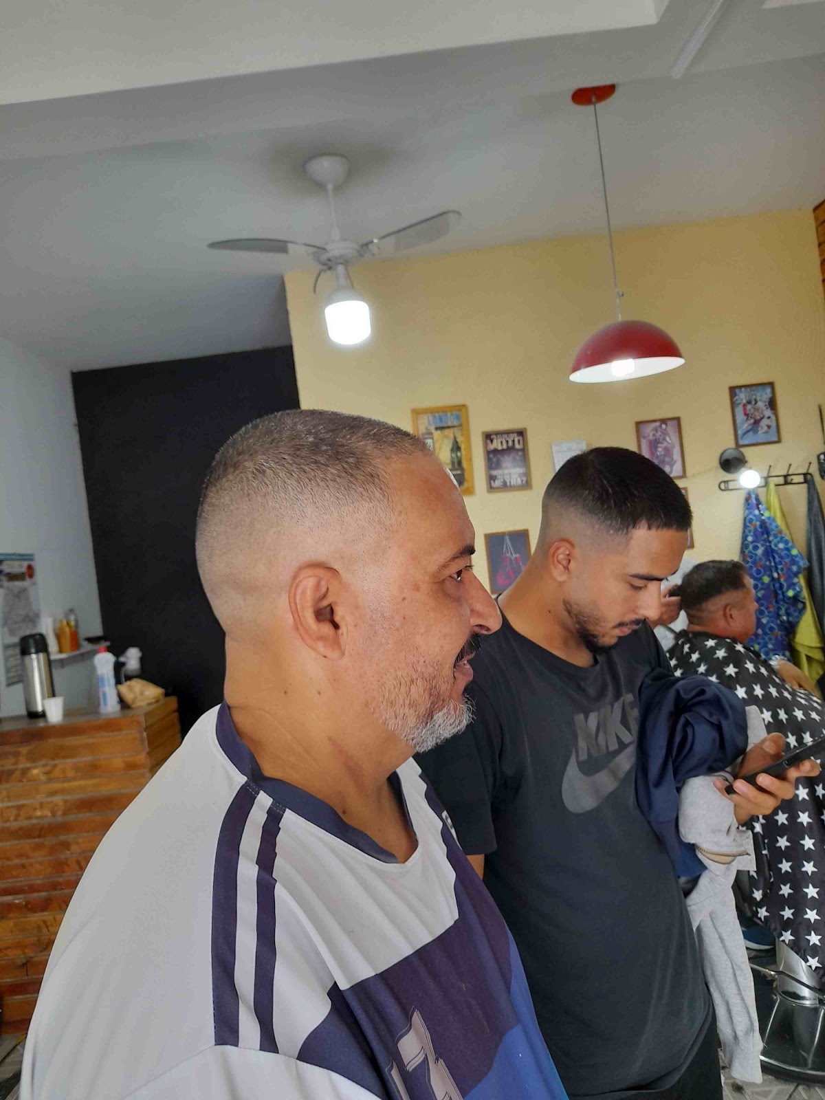 Clientes esperando o atendimento na Barbearia Visual, perto da parede amarela