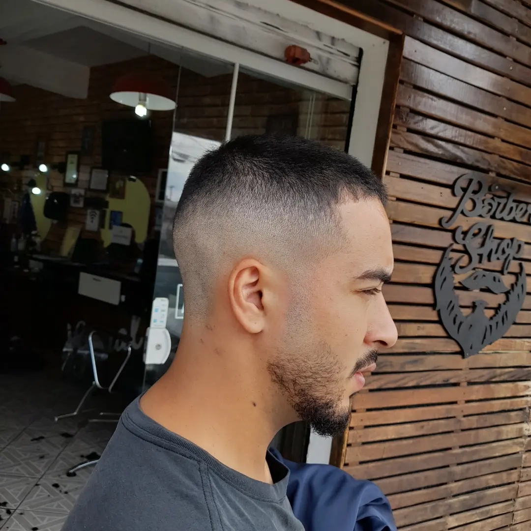 Corte degradê finalizado na porta da Barbearia Visual, com o letreiro Barber Shop ao fundo